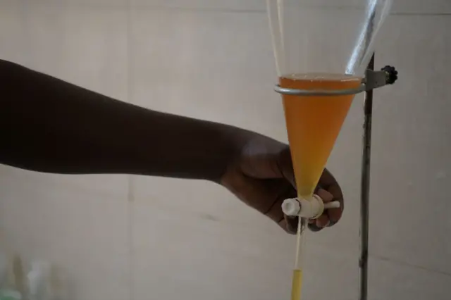 Ikiganza gifashe igikombe kirimo amavuta ya patchouli ameze nk'amazi