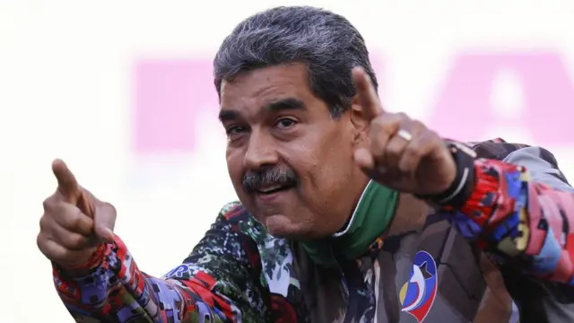 Nicolás Maduro, usando uma jaqueta colorida, levanta os dois dedos indicadorespix bet spacemandireção ao alto