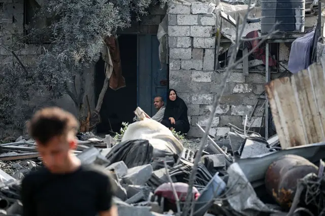 Palestinos sentados entre los escombros de una casa después de un ataque israelí nocturno que golpeó Nuseirat en el centro de la Franja de Gaza el 13 de julio de 2025.