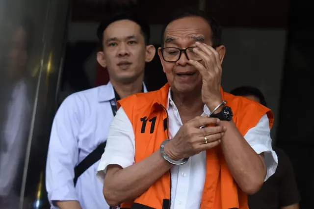 Seorang pria tua dengan rompi jingga keluar dari ruangan.