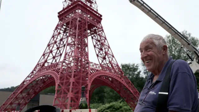 Mężczyzna siedzący przed czerwoną wieżą.