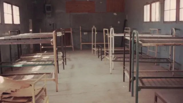 Los barracones en los que jóvenes estudiantes de secundaria vivieron durante seis semanas en Blythe, California, en 1965. La imagen, en la que se ven las literas sin colchones en un espacio con iluminación natural, fue tomada en 1990.