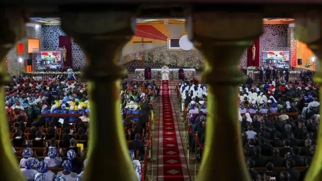 Papa, maaskofu na waumini wanaonekana kupitia uzio ndani ya kanisa kuu mjini Bamenda.