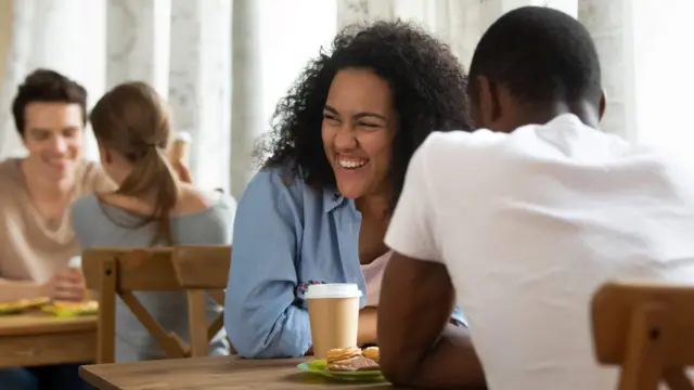 A woman laughs as she talks to a man at a speed dating event