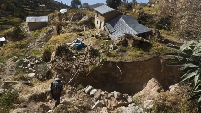 Hombre mirando casas destruidas.