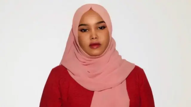 Bella porte un foulard rose qui lui couvre la tête et les épaules.