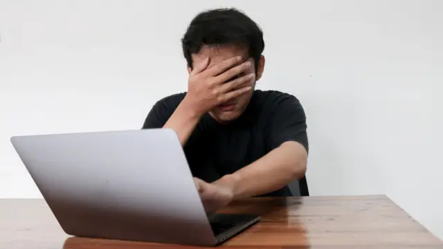 लैपटॉप के पास बैठा व्यक्ति
