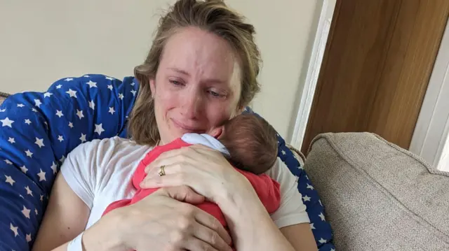 Louise abraza a su bebé recién nacido, mientras llora.