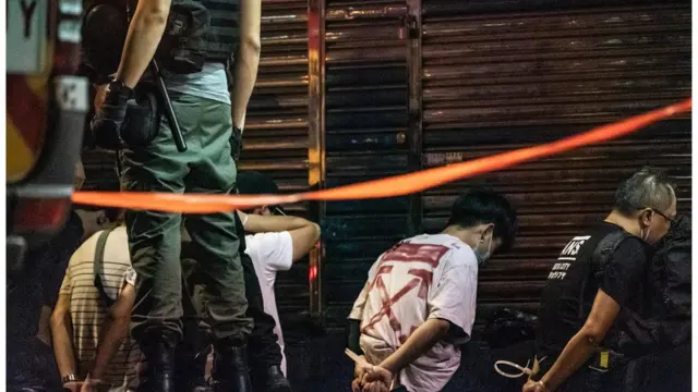 有市民被警方制服后，坐在地上，被绑上手带。