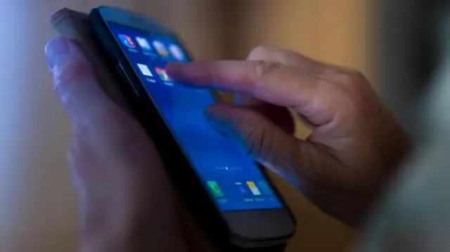 एउटा हातले मोबाइल फोन समातेर अर्कोले चलाउँदै गरेको तस्बिर 