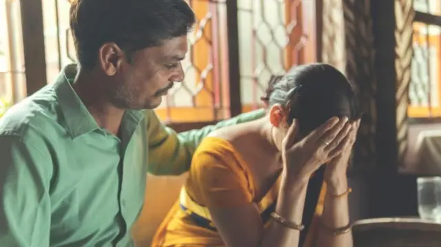 डोक्यावर हात ठेवलेली महिला 