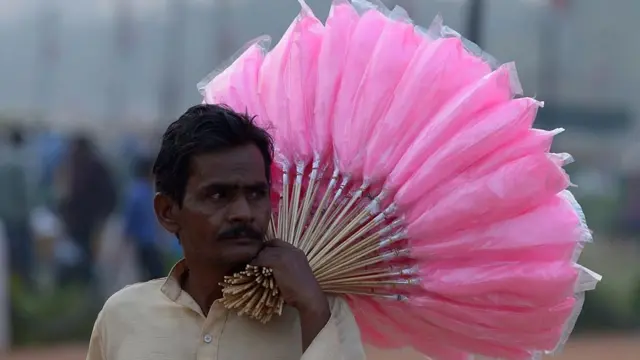 Un vendeur indien transporte des barbes à papa à vendre à la Porte de l'Inde à New Delhi le 28 octobre 2014.