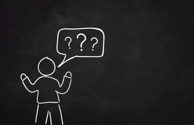 Muñeco pintado en tablero con burbuja de signos de interrogación