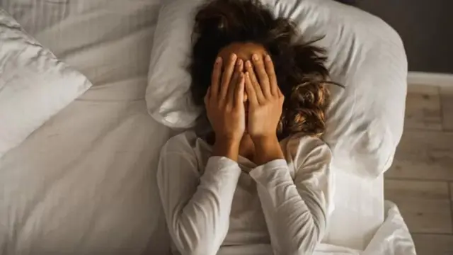Une femme stressée couchée sur le lit.