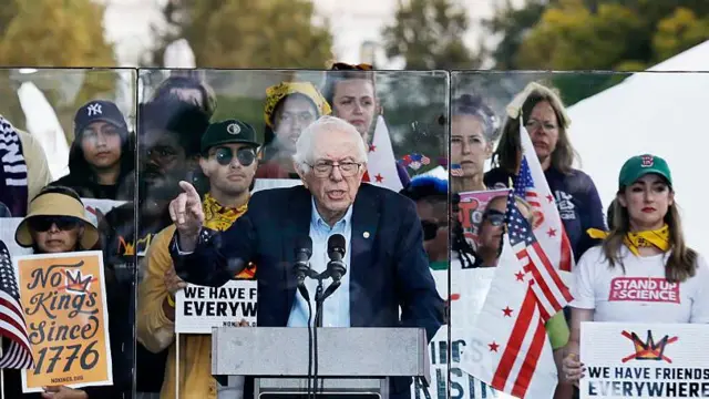 Сандерс в окружении протестующих за пуленепробиваемым стеклом