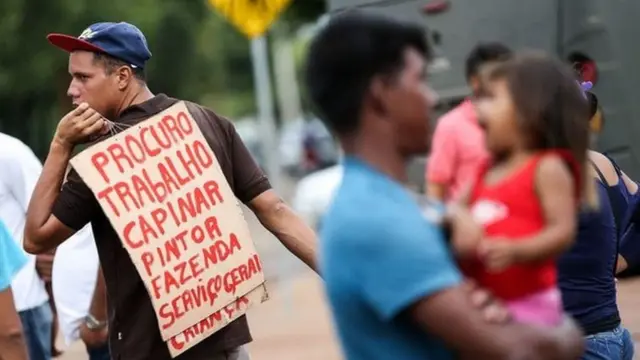 Homem com cartaz que diz 'procuro trabalho'