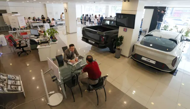 제21대 대통령 선거일인 3일 서울 광진구 기아자동차 대공원대리점에 마련된 능동제3투표소에서 유권자들이 투표를 하고 있다. 아래쪽에 대리점 직원이 고객과 차량 구매 상담을 하고 있다