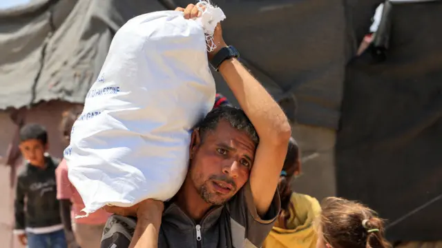 فلسطيني يحمل إمدادات المساعدات التي تلقّاها من مؤسسة غزة الإنسانية في خان يونس