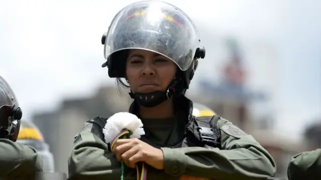 Una funcionaria de la GNB con una flor blanca que le entregó una manifestante de la oposición.