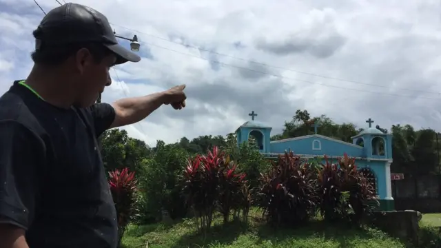 Benjamín Sarat señala al volcán, oculto entre las nubes detrás de la iglesia de El Viejo Palmar.