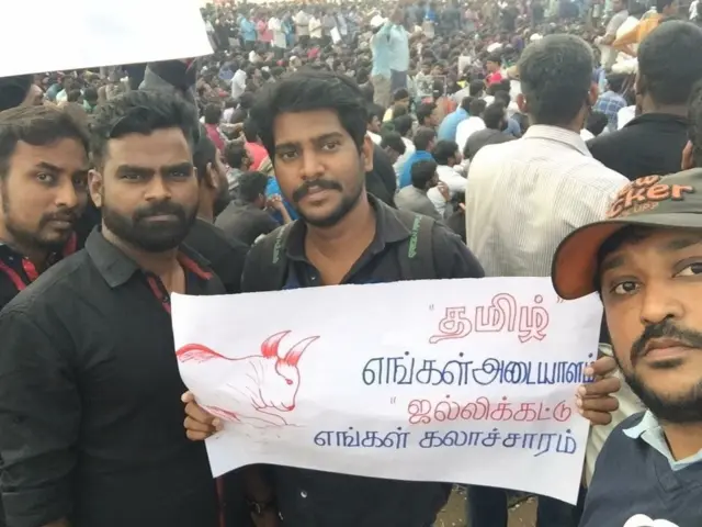 ஜல்லிக்கட்டை தங்கள் கலாசாரத்தின் அடையாளமாக காட்டும் பதாகையுடன் இளைஞர்கள்