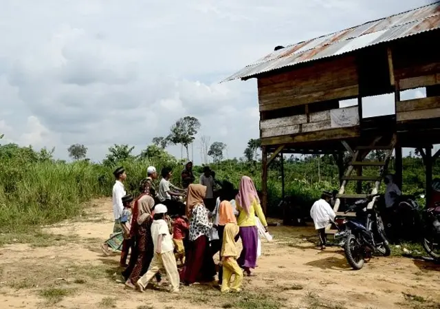Anak-anak dari suku "Orang Rimba" yang namanya diterjemahkan sebagai "orang hutan", yang telah masuk Islam dan meninggalkan cara nomaden mereka, tiba di gubuk kayu mengenakan topi tengkorak Islam dan jilbab saat mereka berkumpul untuk membaca Al-Qur'an, di distrik Batang Hari di provinsi Jambi.