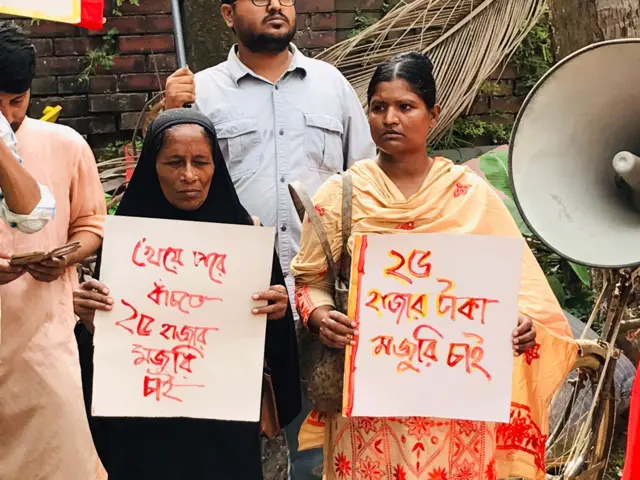 বেতন বৃদ্ধির দাবিতে প্লাকার্ড হাতে দুই পোশাক শ্রমিক