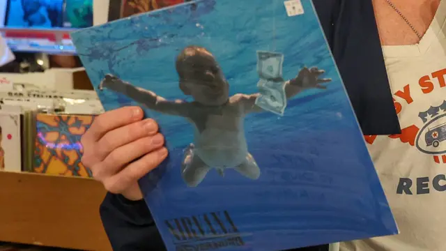 Ręka trzymająca winylowy album Nevermind zespołu Nirvana w sklepie muzycznym.