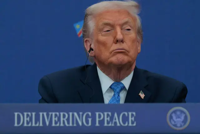 Trump, sobre un rótulo con el mensaje "delivering peace" ("entregando paz).