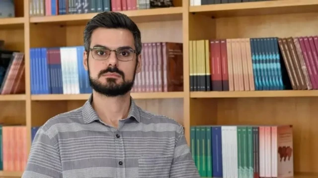 Pedro Ferreira de Souza em frente a uma estante de livros