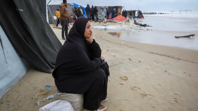 سيدة في خان يونس تنظر للبحر وسط خيام النازحين