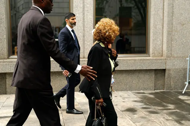 Janice Combs vista de lado, com outras duas pessoas, indo em direção a tribunal