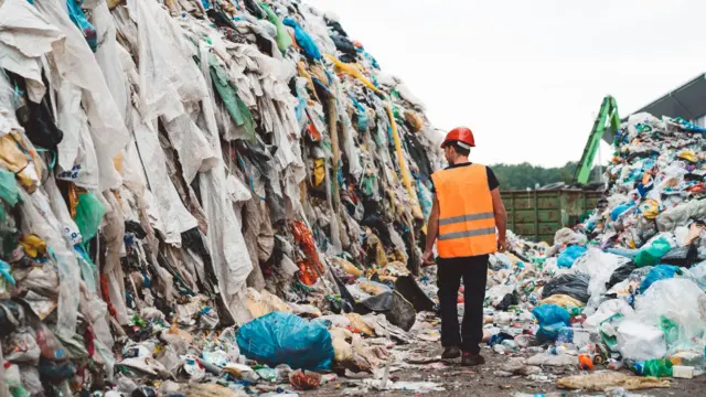 Aterro sanitário com várias roupas jogadas fora. 