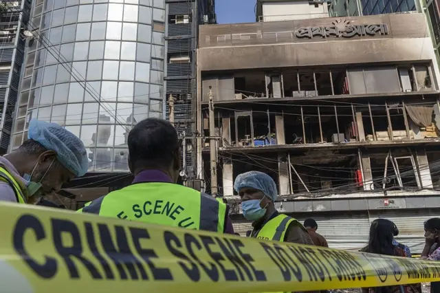 প্রথম আলোর পুড়ে যাওয়া কার্যালয়ের সামনে দাঁড়িয়ে আছেন সিআইডির কয়েকজন সদস্য, ক্রাইম সিন লেখা ফিতা দিয়ে এলাকাটি ঘেরা