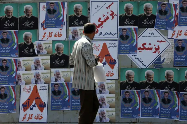 مواطن أمام ملصقات المرشحين للانتخابات الرئاسية الرابعة عشرة في الشوارع قبل الانتخابات الرئاسية المبكرة في طهران، إيران في 27 يونيو 2024.