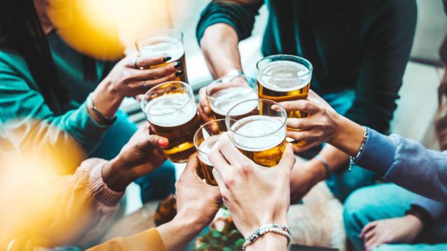 Un grupo de personas brindando con vasos llenos de cerveza.