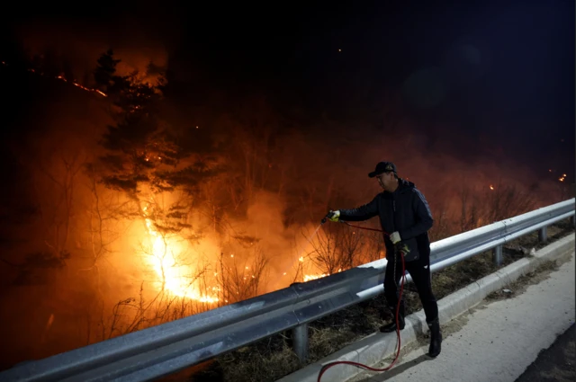 한 주민이 산불 확산을 막기 위해 물을 뿌리고 있다