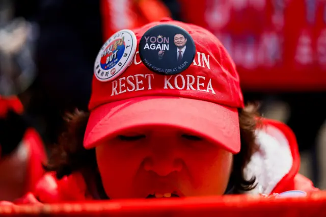 Женщина в красной кепке со значками в поддержку Юна