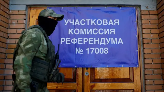 A service member of the self-proclaimed Donetsk People's Republic walks past a polling station ahead of the planned referendum in Donetsk