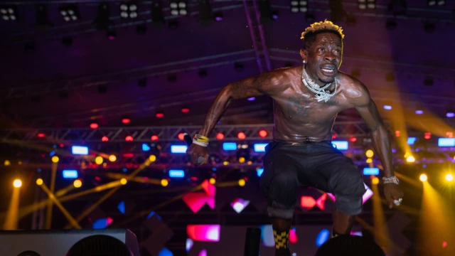 Shatta Wale perform to a crowd at an event, jumping and showing energy on stage