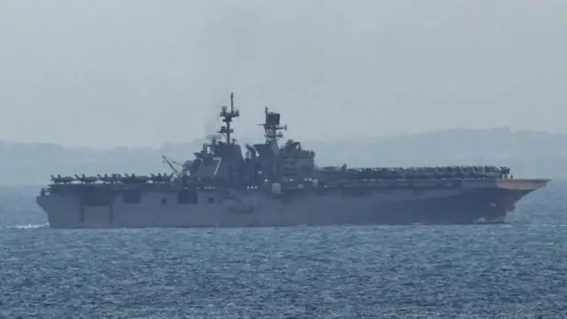 Десантный корабль USS Tripoli в море на фоне суши в дымке