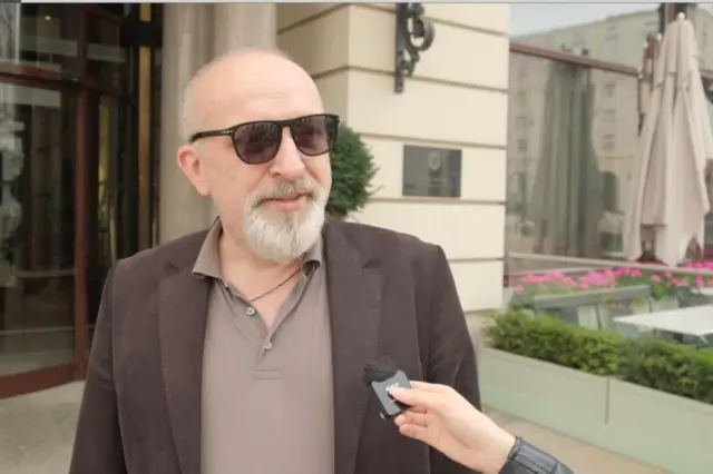 Чоловік у сонцезахисних окулярах і коричневому піджаку