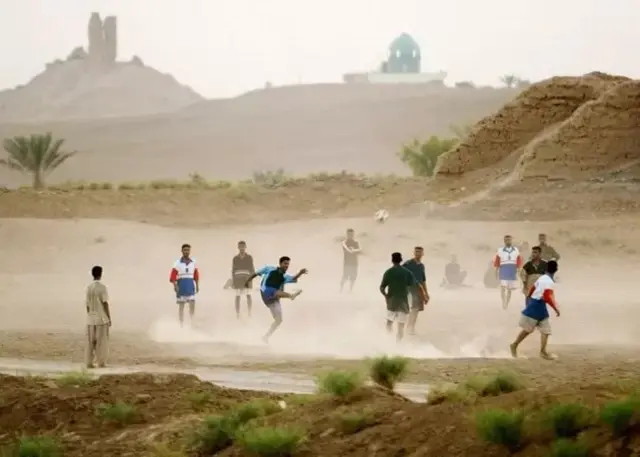 Jeunes irakiens jouant au football près d'une ziggourat.