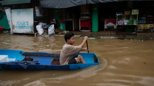 Seorang pria sedang mendayung di tengah kota yang kebanjiran.