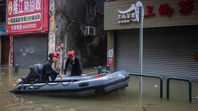 Dos bomberos en una lancha recorren las calles inundadas en una ciudad de China