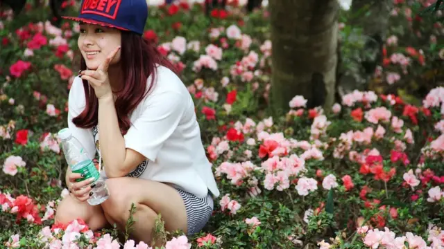 seorang wisatawan berfoto di tengah kebun bunga