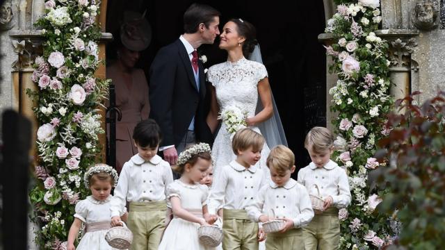 Pippa Middleton and James Matthews in the arch of the church they married in with seven page boys and bridesmaids in front of them.
