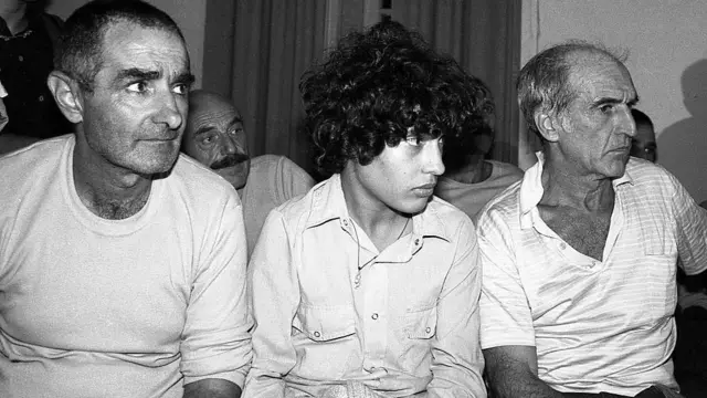 さまざまな年齢の男性たちが座っている様子を映したモノクロ写真