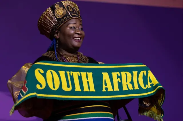 South African football fan Mama Joy Chauke holds up a scarf with the words "South Africa" knitted into it.