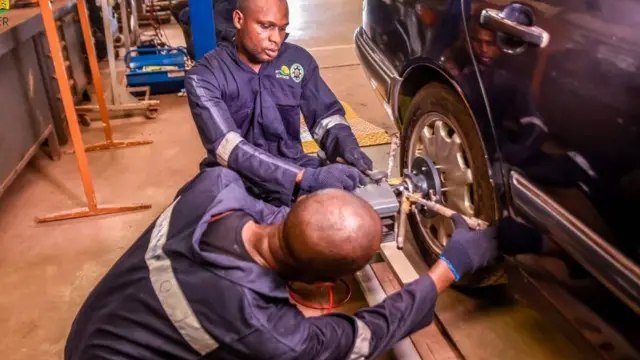 Two men dey work ontop motor